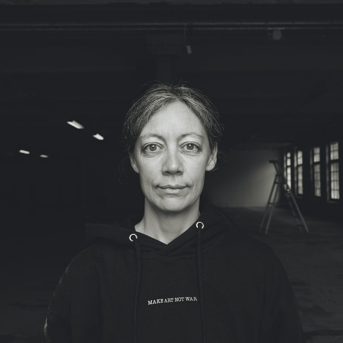 A woman in a dark hoodie with gray hair.